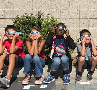 four students with sunglasses on watching the eclipse